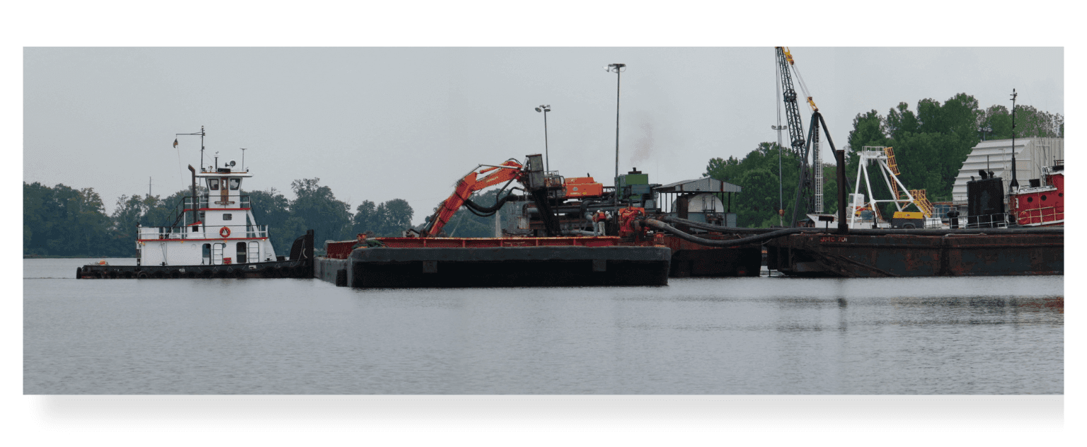 A towboat and loaded material barges alongside the dock at Port Tobacco on the James River.